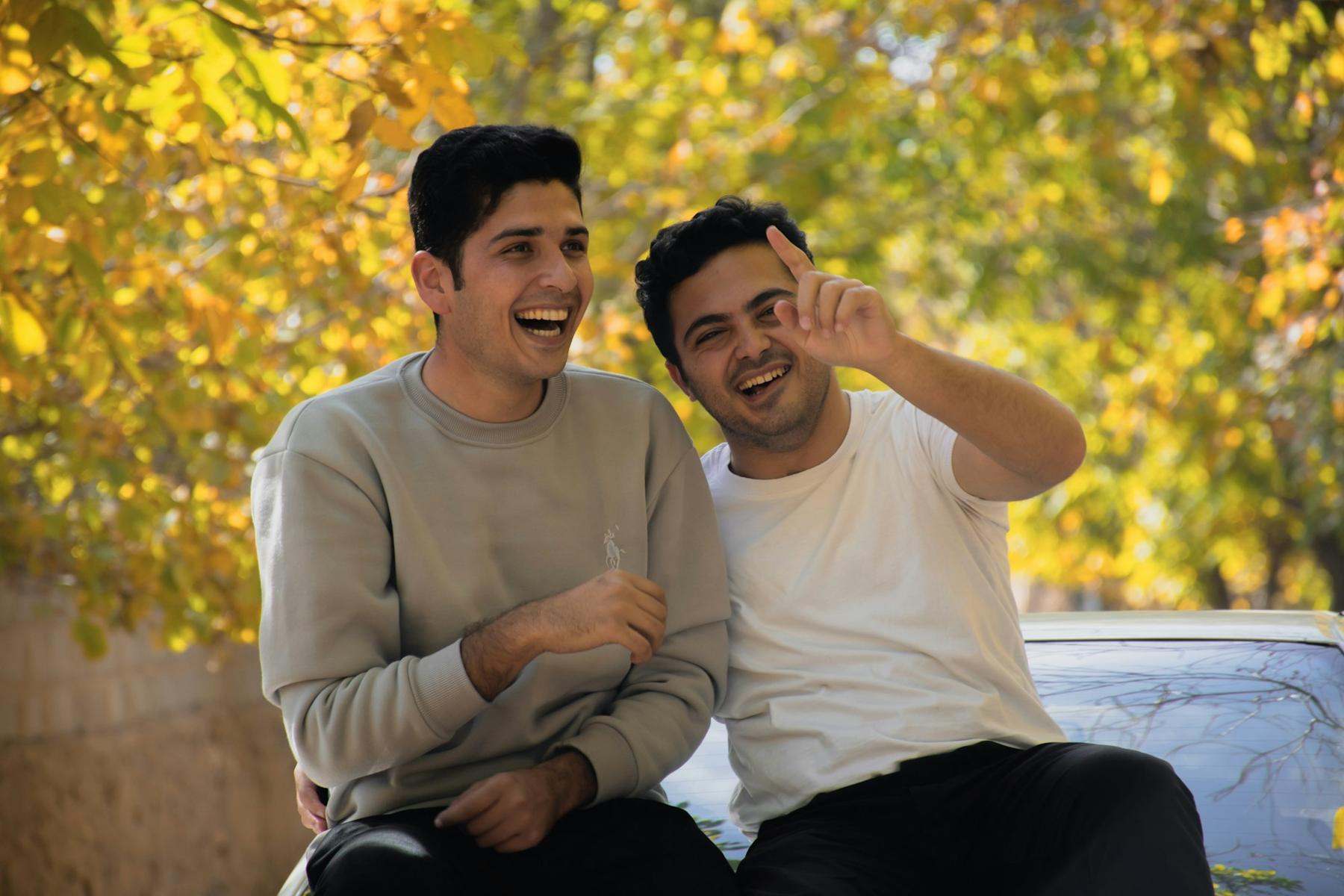 Two friends laughing together on a bench in autumn