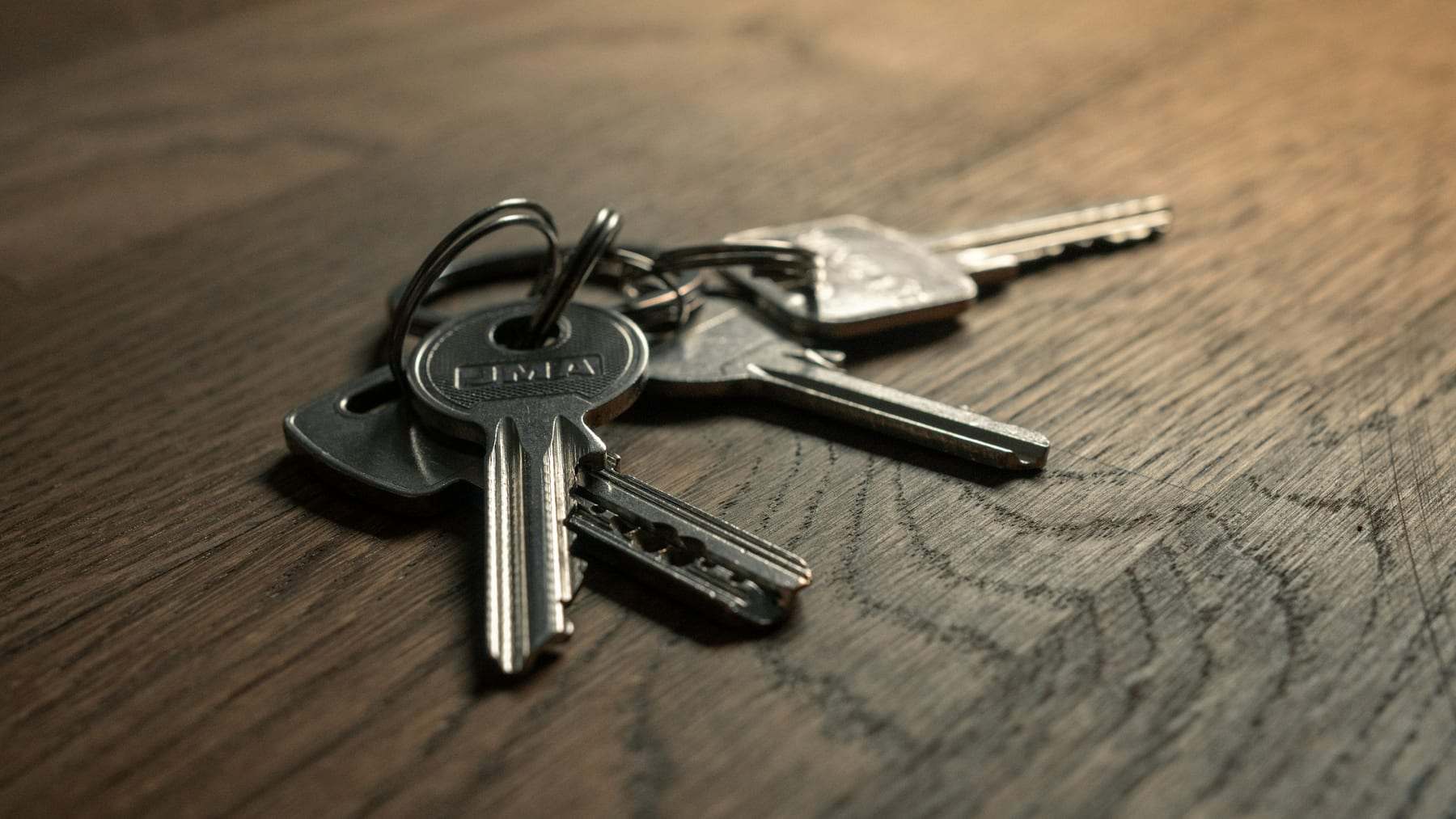 A bunch of house keys lying on a dark wooden table