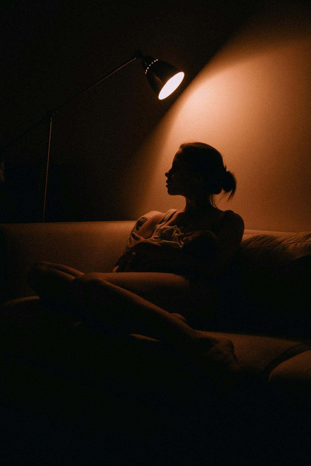 A silhouette on a sofa at night